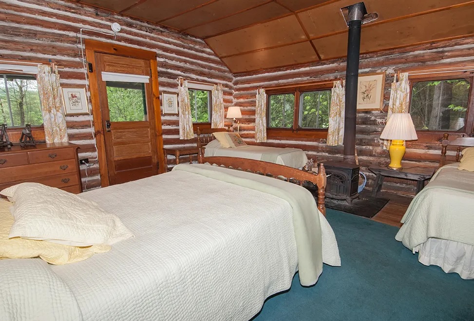 Log Hall bedroom with beds and warm wood walls