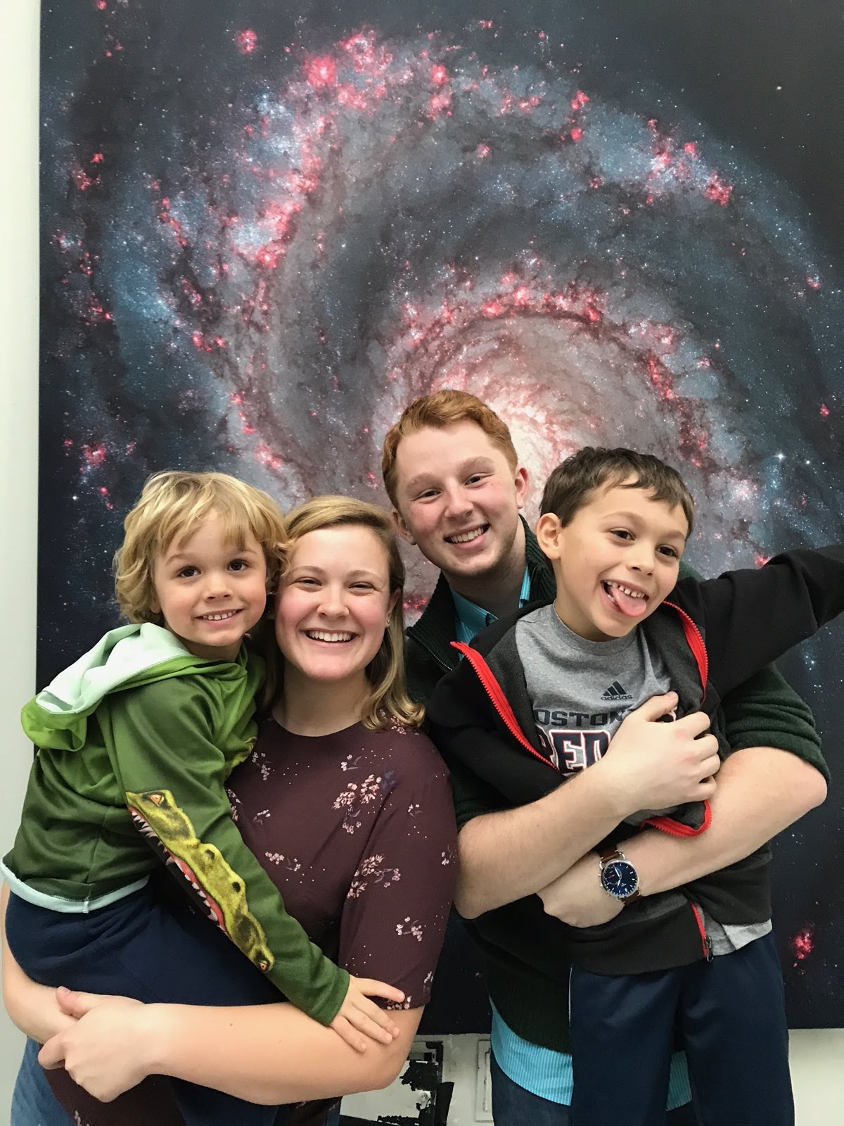Anna and Alex with Anna's brothers in front of a galaxy mural