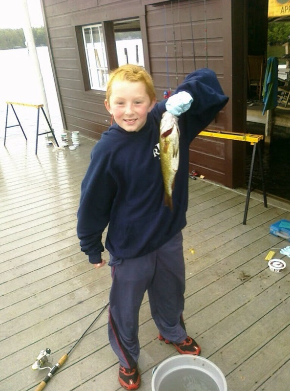Young Alex holding a fish on the dock at camp